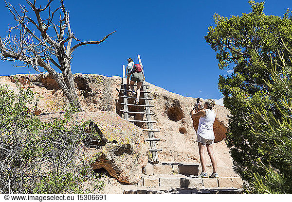 Family exploring the Tsankawi Ruins in New Mexico climbing up steps.