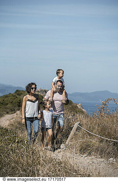 Family hiking at trail against blue sky
