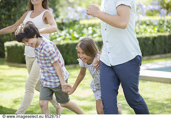 Family holding hands and running in backyard