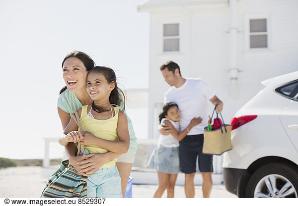 Family hugging in sunny driveway