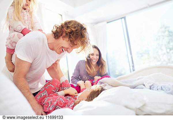 Family laughing and playing on bed