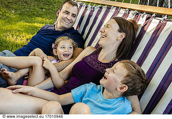 Family laughing while relaxing on hammock during weekend