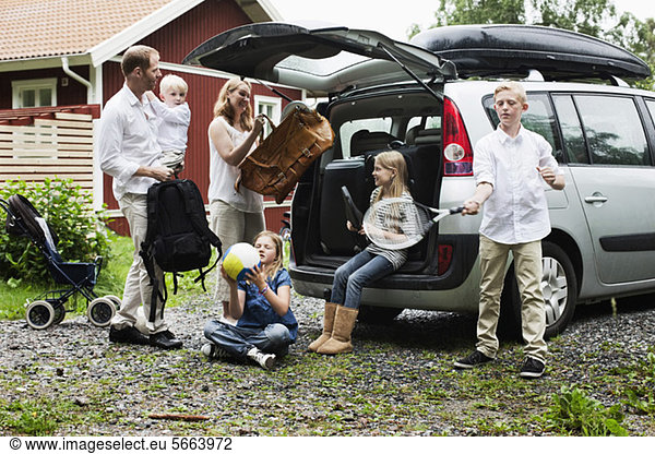 Family loading luggage in car trunk for vacation