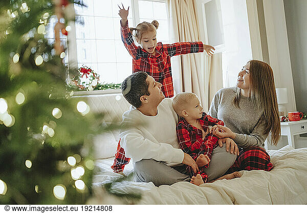 Family looking at daughter dancing on bed