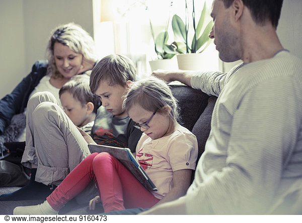 Family of five sitting on sofa at home