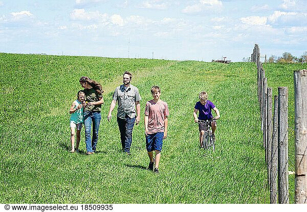 Family of five walking in a field in the country.