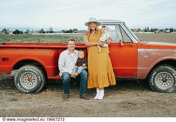Family of four by old red truck at corn maze