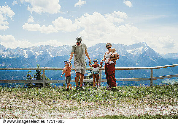 Family of 5 standing on Alps mountain top in summer