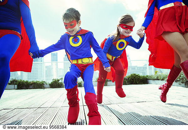 Family of superheroes running on city rooftop