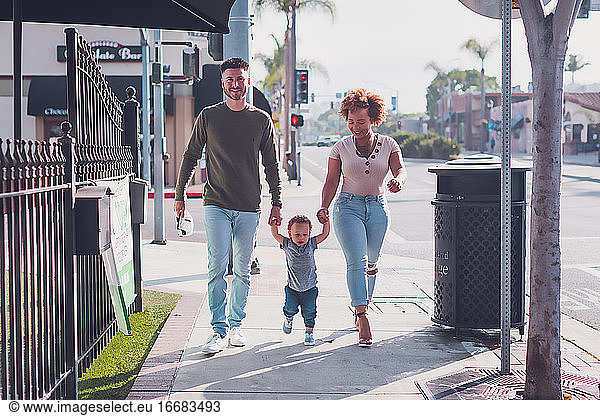 Family of three walking in Downtown,  baby boy walking with parents
