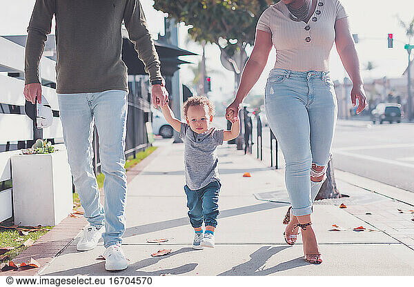 Family of three walking in Downtown  baby boy walking with parents