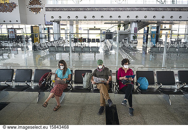 Family of three wearing face masks due to the Coronavirus global health crisis while waiting at a deserted airport in Khajuraho  Madhya Pradesh  India.