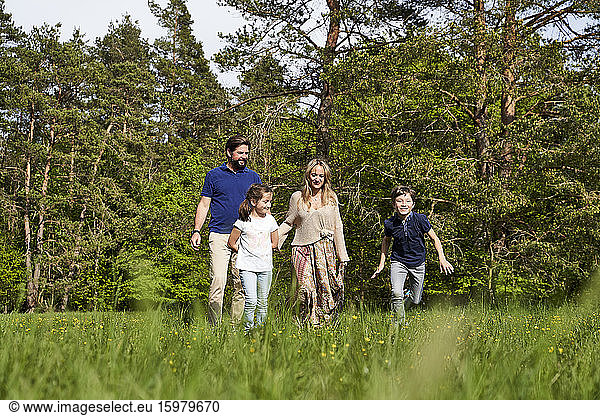 Family on grass against trees during sunny day