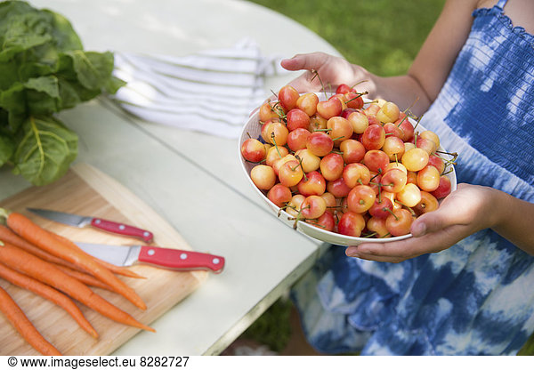 Family Party. A Child Carrying A Bowl Of Fresh Picked Cherries To A Buffet Table.