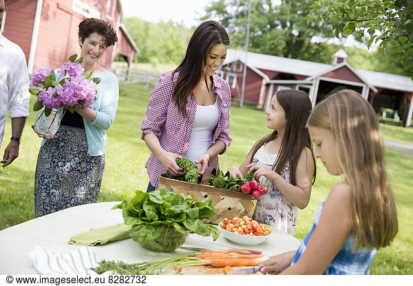 Family Party. Five People  Parents And Children Around A Table Preparing A Meal Of Fresh Picked Salads  Fruits And Vegetables Together.