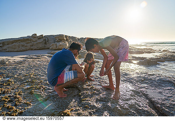 Family playing on rocks on sunny beach