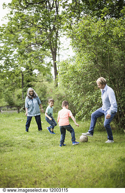 Family playing soccer in back yard