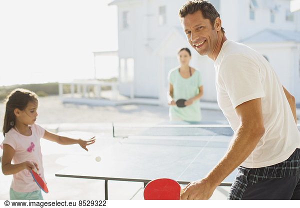Family playing table tennis outside house