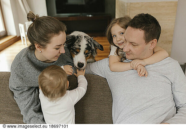 Family playing with Australian Shepherd in living room at home