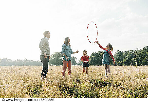 Family playing with hula hoop in park at weekend