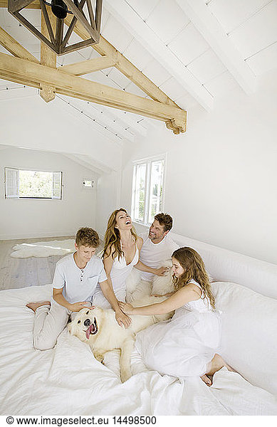 Family Playing with Pet Dog on Bed
