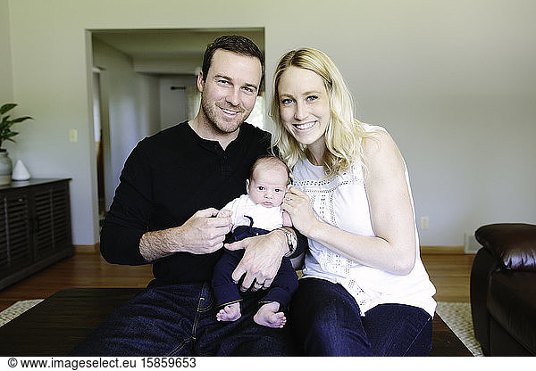 Family portrait of first time parents and their newborn son at home