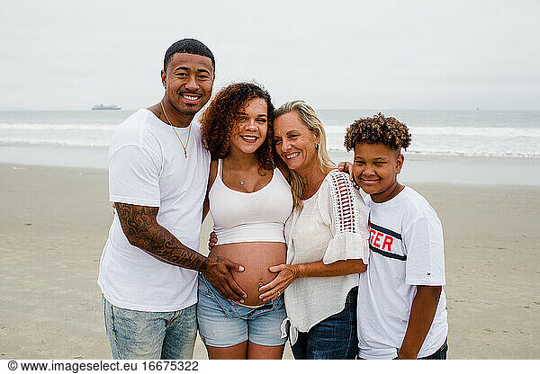 Family Posing for Maternity Photos on Beach