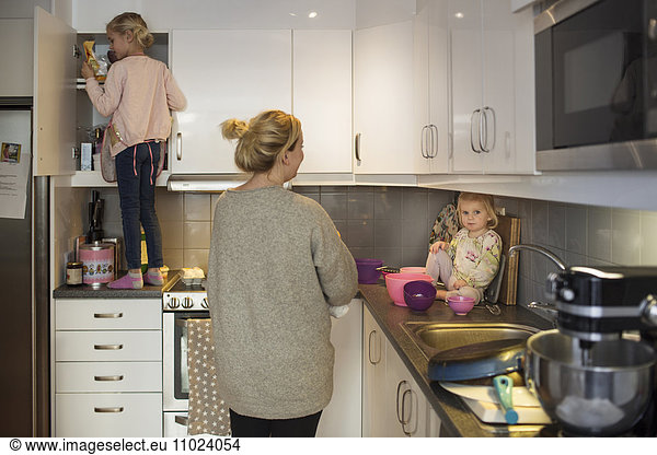 Family preparing pancake together in kitchen