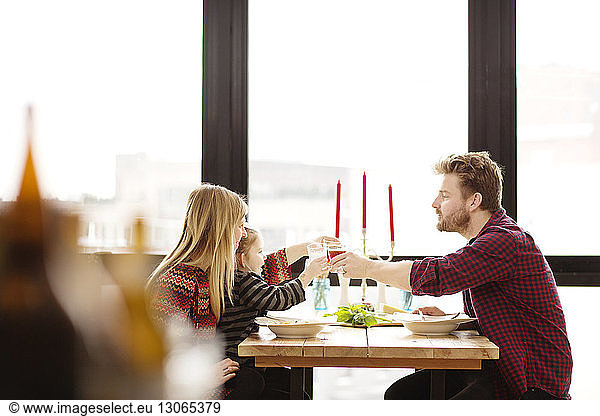 Family raising toast at dinning table in home