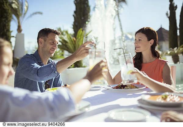 Family raising toast at table outdoors
