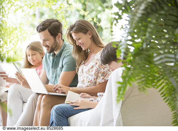 Family reading and using technology on patio