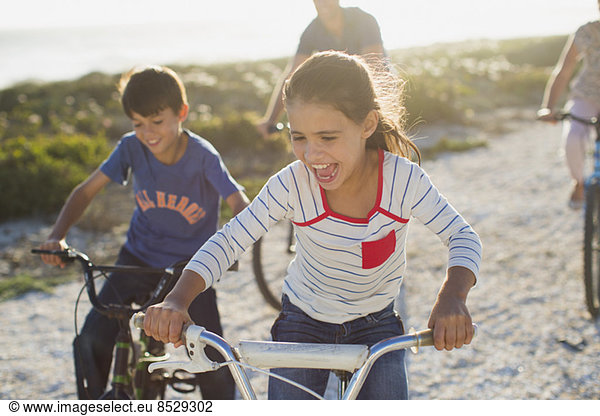 Family riding bicycles on sunny beach