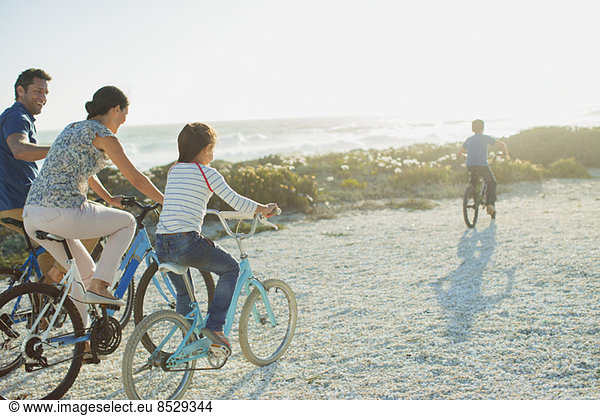 Family riding bicycles on sunny beach