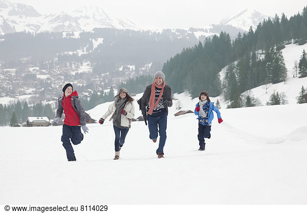 Family running in snowy field