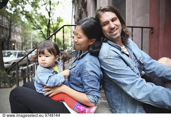 Family sitting on front stoop in city