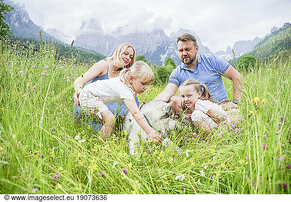 Family spending leisure time with dog sitting on grass