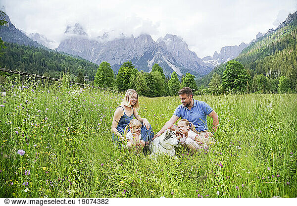 Family spending vacation sitting on grass in front of mountains