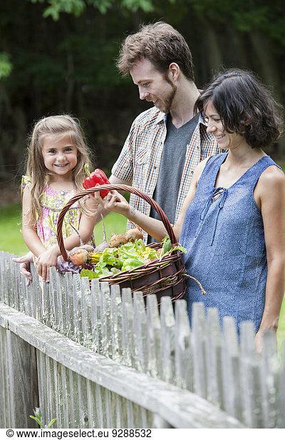 Family standing in a garden with a basket of vegetables.