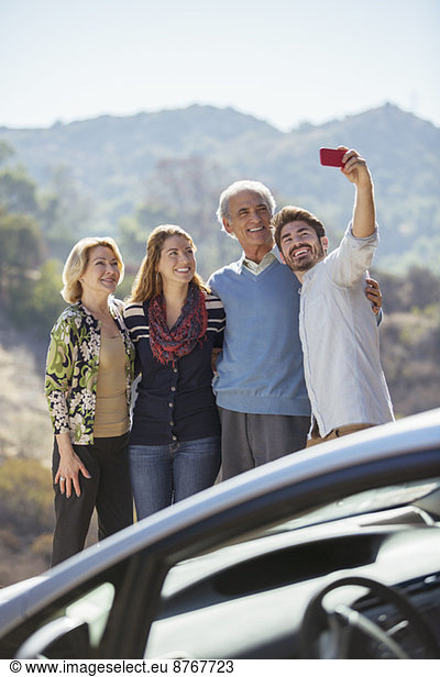 Family taking self-portrait with cell phone outside car