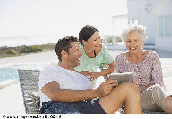 Family using digital tablet at poolside