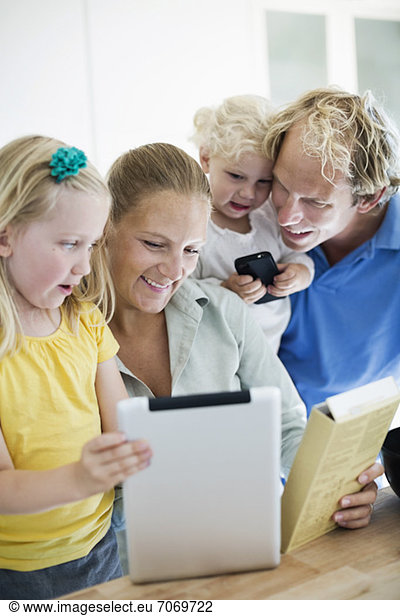 Family using digital tablet for cake making recipe in kitchen