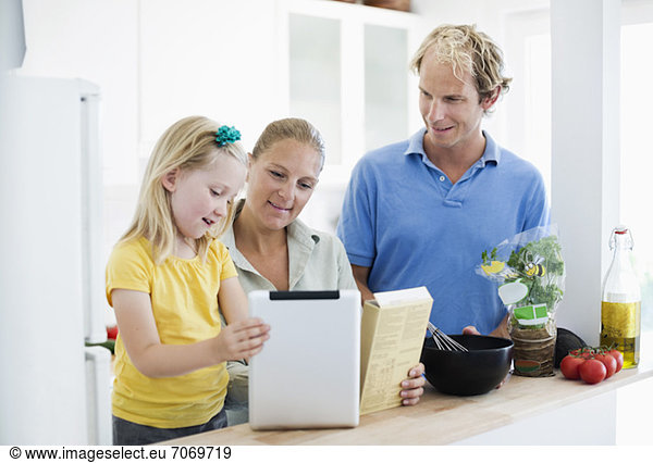 Family using digital tablet for recipe in kitchen