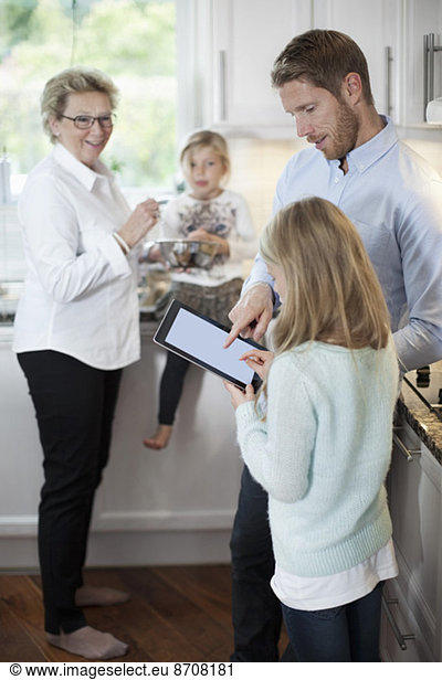 Family using digital tablet while cooking in kitchen