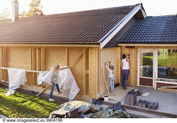 Family using hammer on walls of house being renovated