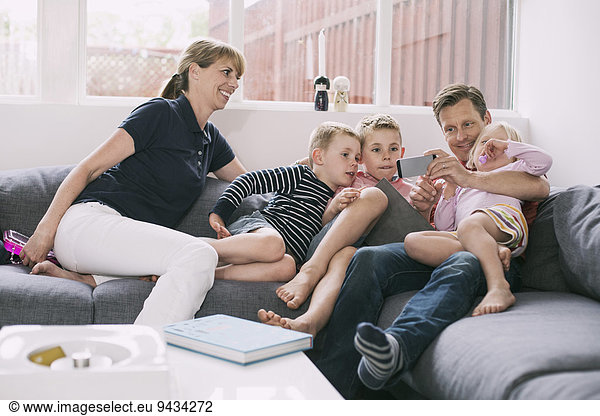 Family using smart phone on sofa at home
