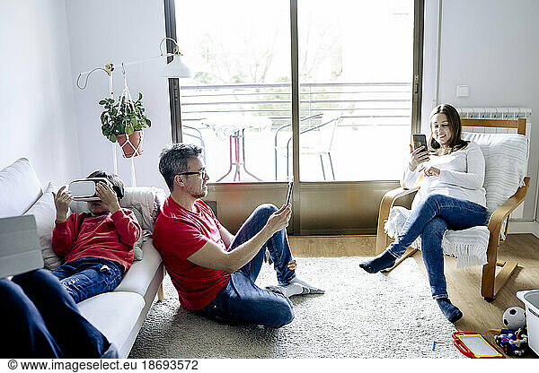 Family using wireless technologies in living room at home