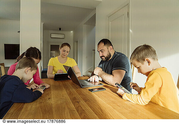 Family using wireless technologies on table at home