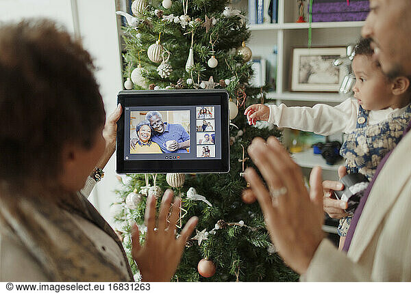 Family video chatting with digital tablet by Christmas tree