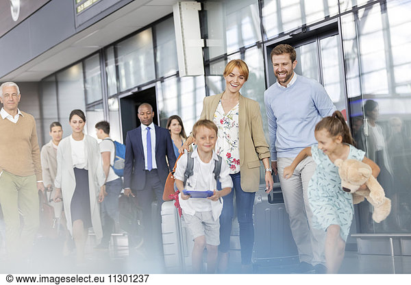 Family walking and running in airport concourse