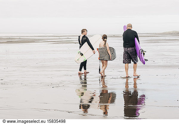 Family walking down the beach with surf and boogie boards